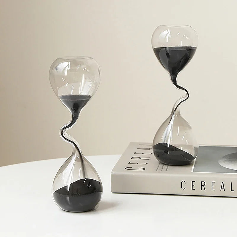 Two modern hourglass designs on a white surface with a book titled 'Cereal' in the background.