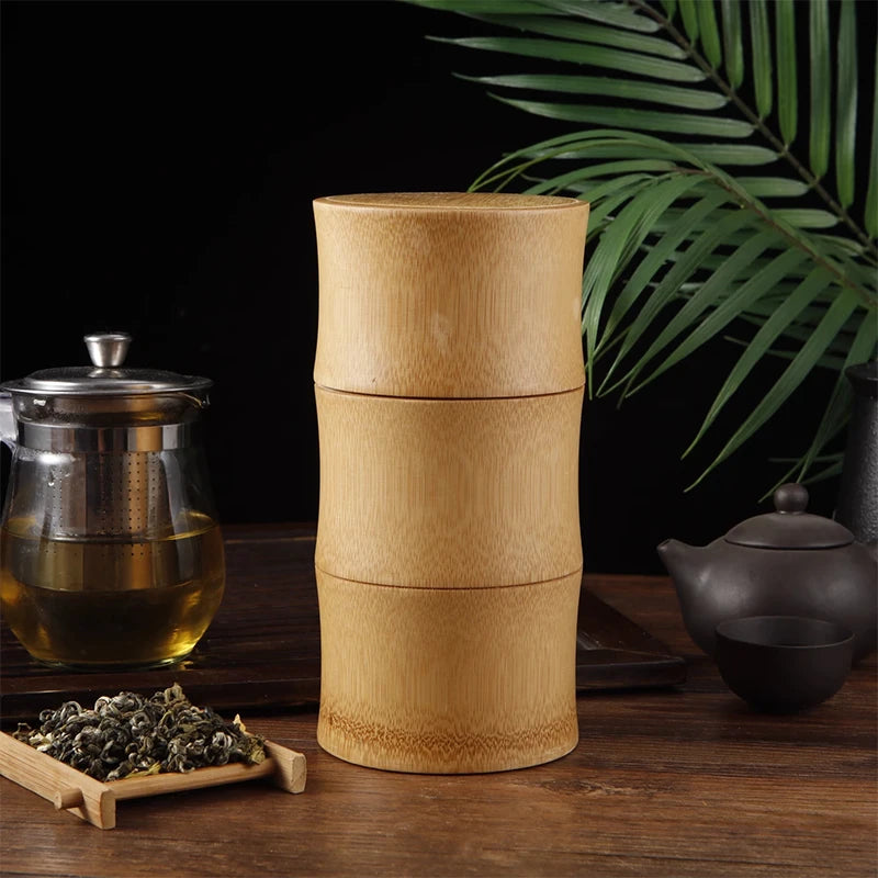 Bamboo tea container on a wooden table with tea-making items and leaves.