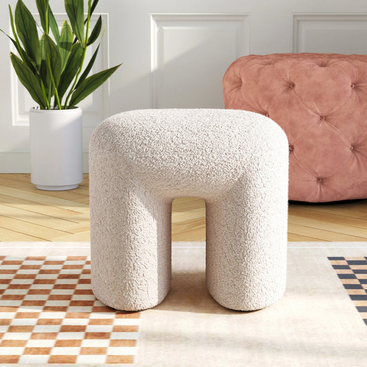 White textured stool in a room with a pink tufted chair and plant.