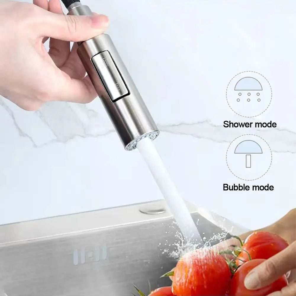 Hand holding a handheld showerhead with water flowing, above a sink with tomatoes.