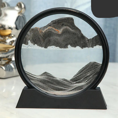 Decorative sand art with mountain landscape inside a circular frame on a stand.
