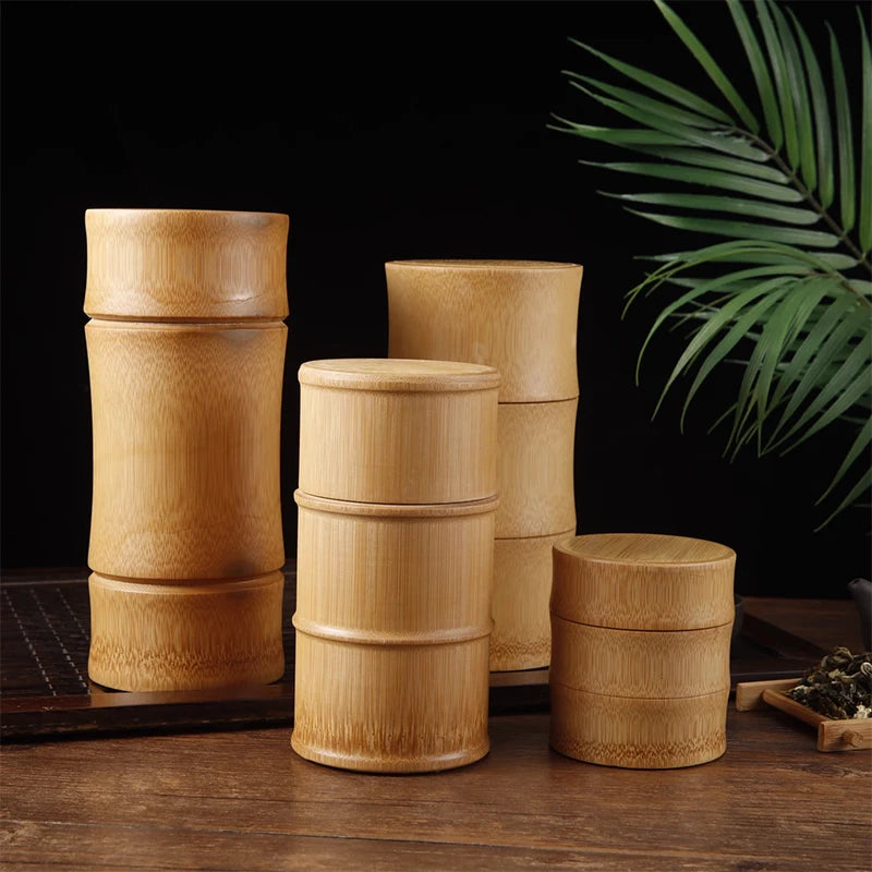 Set of bamboo containers on a wooden surface with a dark background and green leaves.