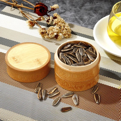 Wooden container with sunflower seeds on a textured surface with a cup of tea in the background.