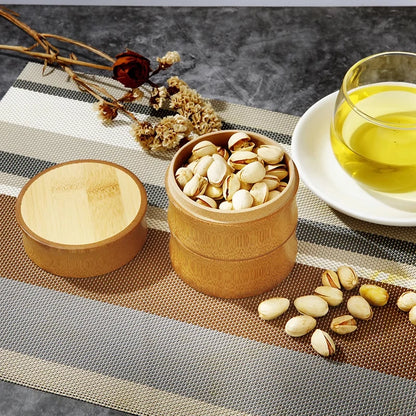 Wooden container with pistachios on a table with a cup of tea and dried flowers.